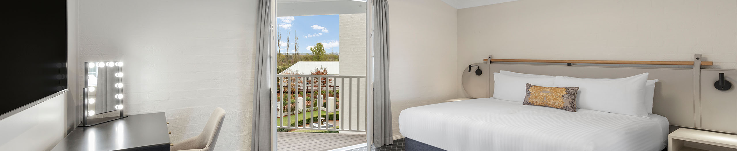 Light coloured hotel room with a wide bed for two people