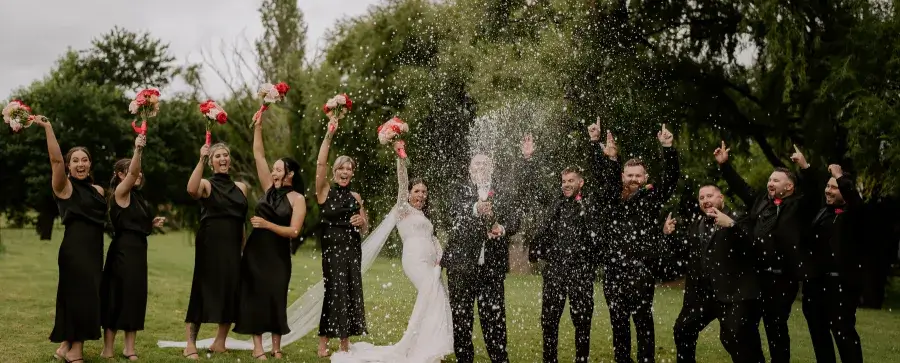 Wedding party celebrating with champagne, throwing bouquets in the air. 